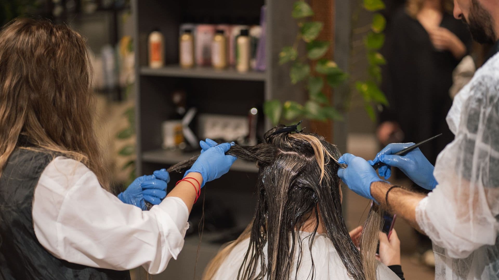 Duas cabeleireiras de luvas a pintar o cabelo de uma cliente num salão