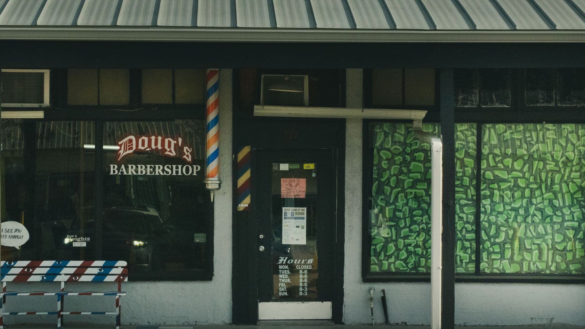 Fachada de uma barbearia com montra e toldo verde