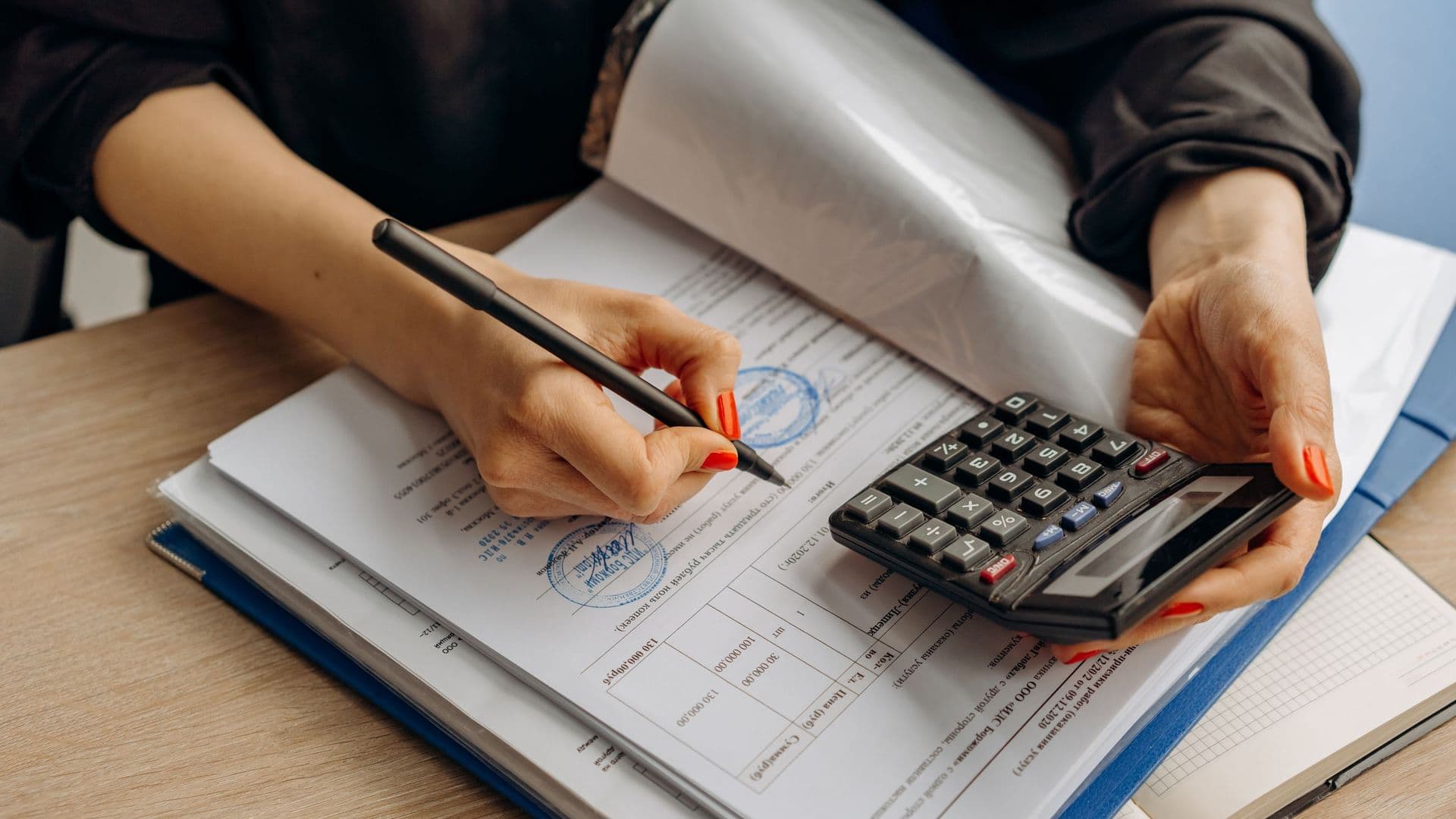 Pessoa a fazer contas com uma calculadora sobre documentos