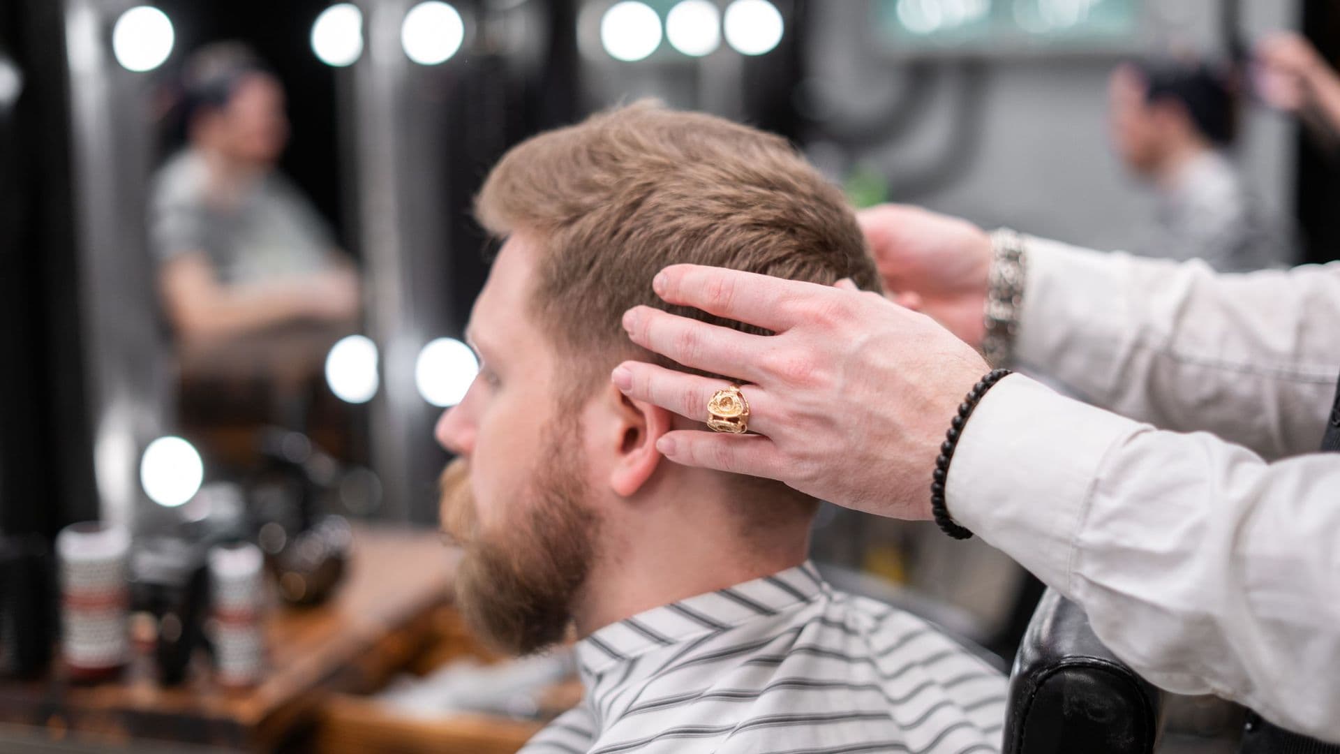 Barbeiro a arranjar o cabelo de um cliente de barba numa barbearia moderna