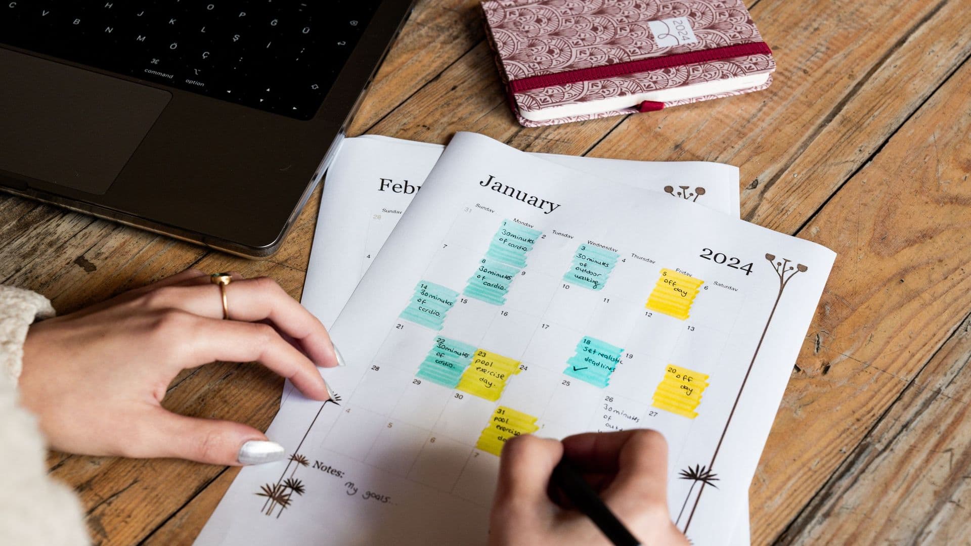 Mãos a marcar compromissos numa agenda de papel com post-its coloridos