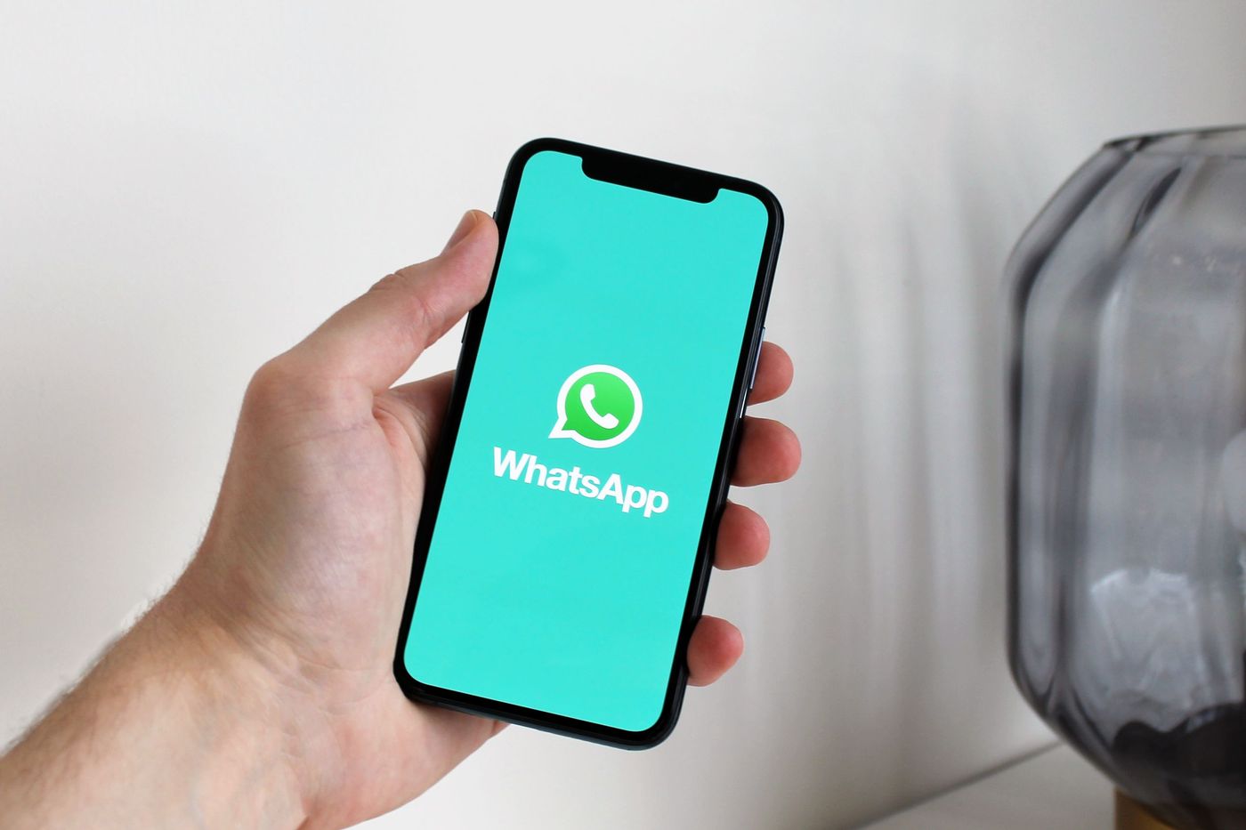 Mão a segurar um telemóvel com o WhatsApp aberto