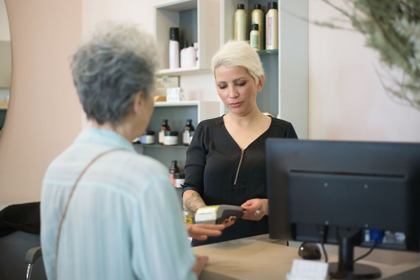 Cliente pagando com cartão no balcão de um salão de beleza