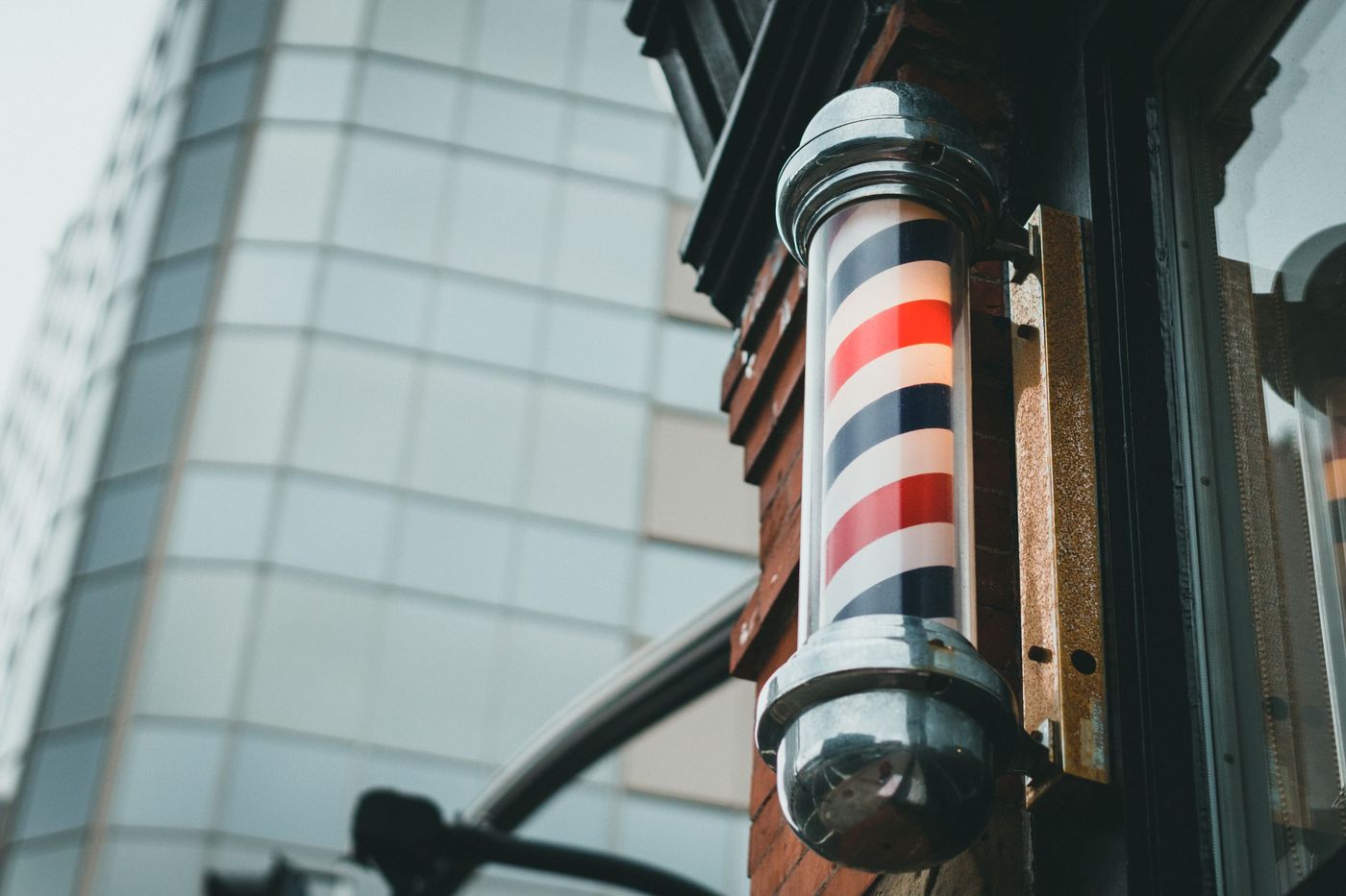 Poste de barbearia clássico às riscas vermelhas, brancas e azuis numa fachada