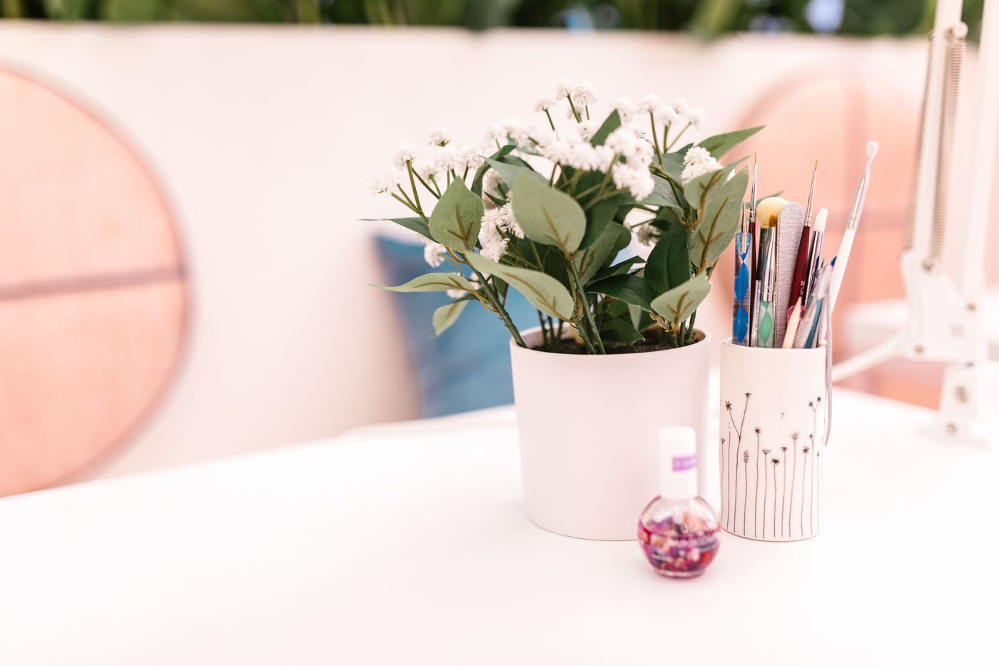 Posto de manicure branco e rosa com plantas e pincéis