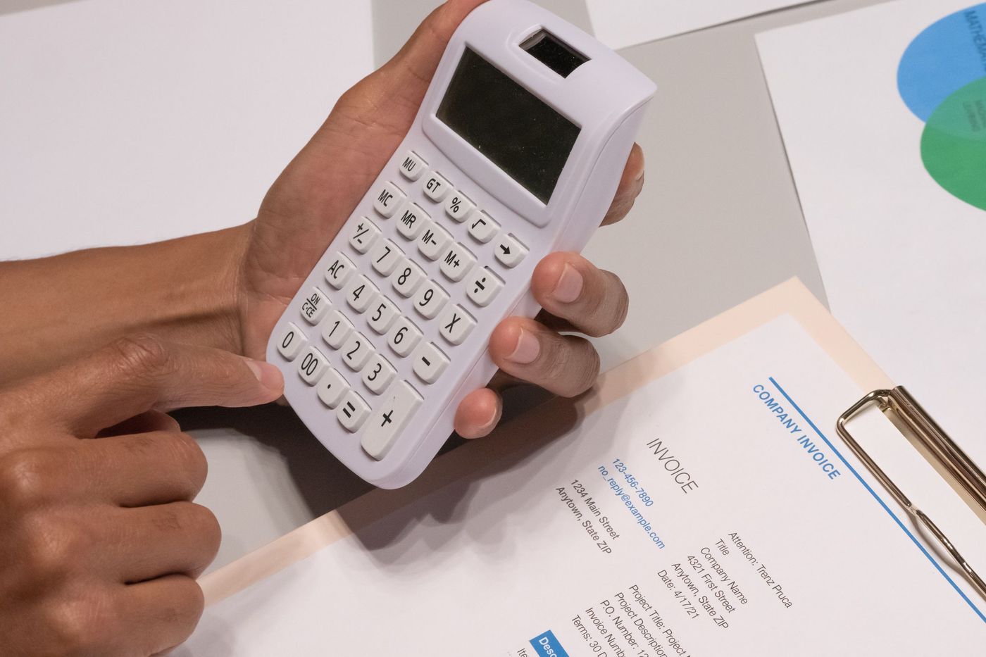 Mãos a usar uma calculadora ao lado de uma fatura