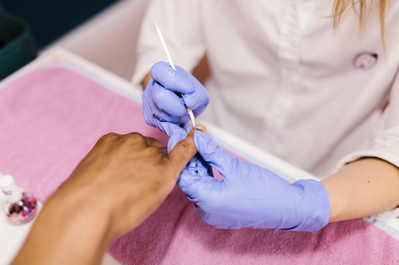 Manicure de luvas fazendo a cutilagem de uma cliente