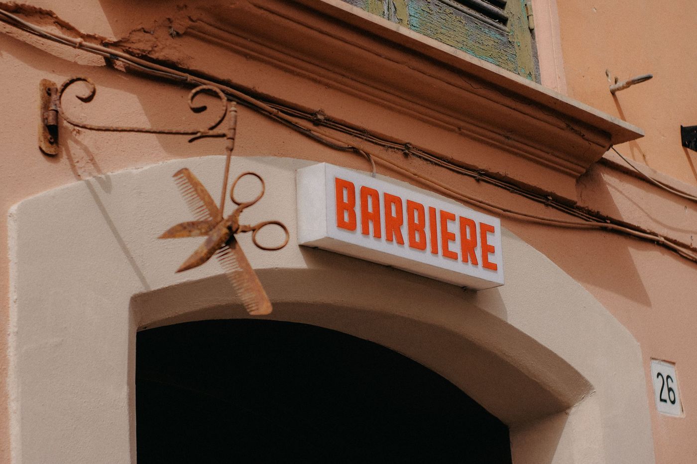 Letreiro antigo de barbearia com uma tesoura de ferro na parede de um prédio